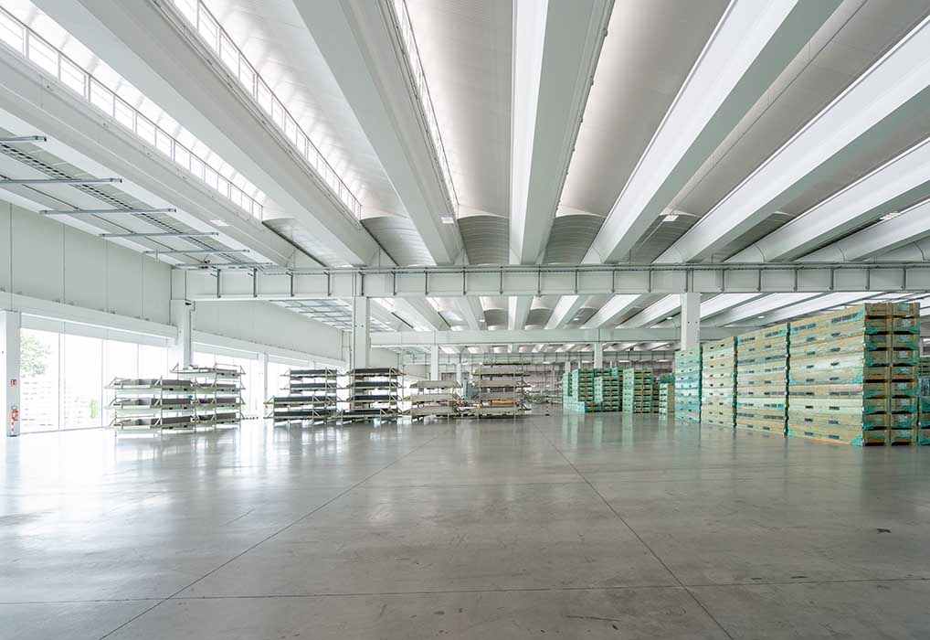 Florim S.p.A. | La copertura è realizzata con tegoli in c.a.p. del tipo MAXIALARE di altezza 120 cm, coibentati e raccordati con pannelli sandwich PIR B Roof, T3, predisposti per l’alloggio dei pannelli fotovoltaici - vista magazzino - Modulo Engineering prefabbricati